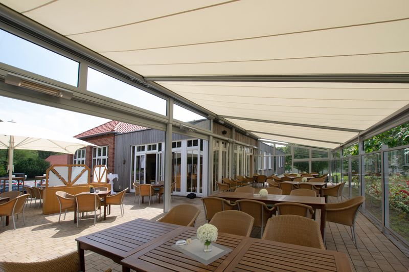 Reference image of the markilux 8800 and 876 on-glass awning with cream fabric cover over a courtyard