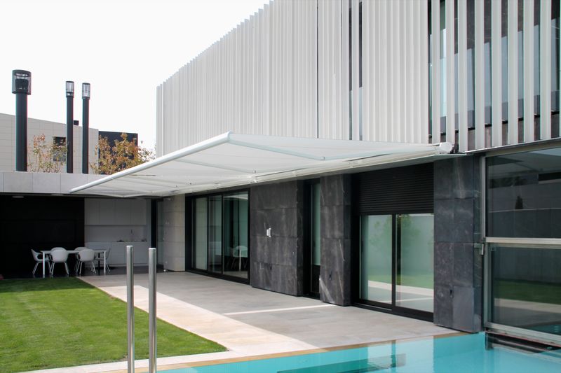 Reference image of cassette awning markilux 5010 (white) on a modern house with pool in the foreground.