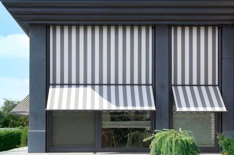 Reference picture: Corner extension with window fronts equipped with marquisolettes markilux 740, gray and white striped fabric cover.