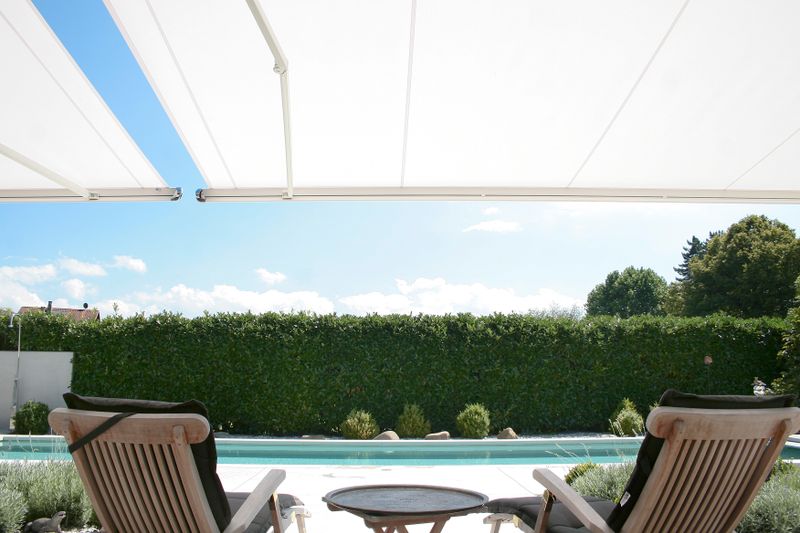 toldo semi-cofre blanco markilux 1600 perspectiva bajo el toldo con vistas a la piscina.