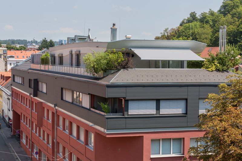 Tenda ombrellone markilux planet con ombrissima su una terrazza sul tetto. Impressione generale della terrazza con vista dall'edificio di fronte.