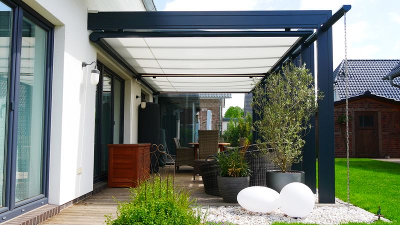 Underglass awning markilux 879 with white fabric cover attached to a patio roof. The frame of the awning is color matched to the black patio roof.