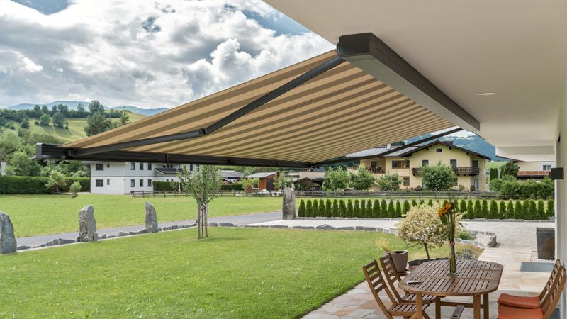 Cassette awning markilux 970 extended brown striped in front of alpine panorama