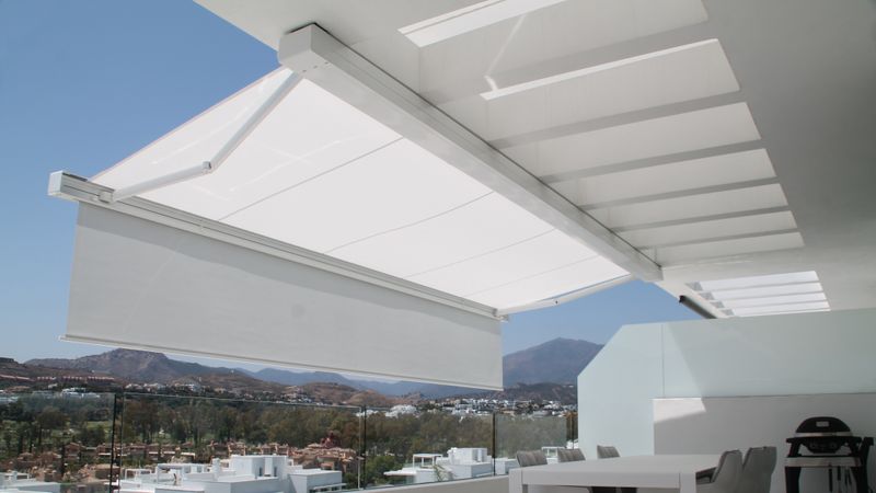 Cassette zonnescherm markilux 970 wit met lichtgrijze kap plus op overdekt terras in Marbella, Spanje