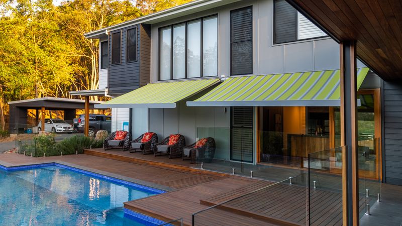 Cassette awning markilux 970 green-blue striped on hotel courtyard with pool