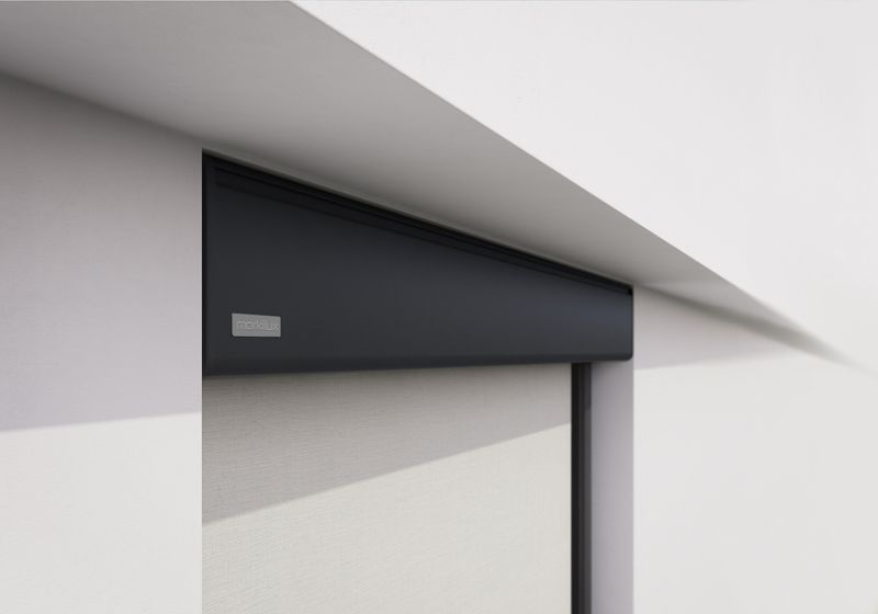 Detailansicht einer grauen markilux Vertikalmarkise in einer Nische einer weißen Hauswand montiert.