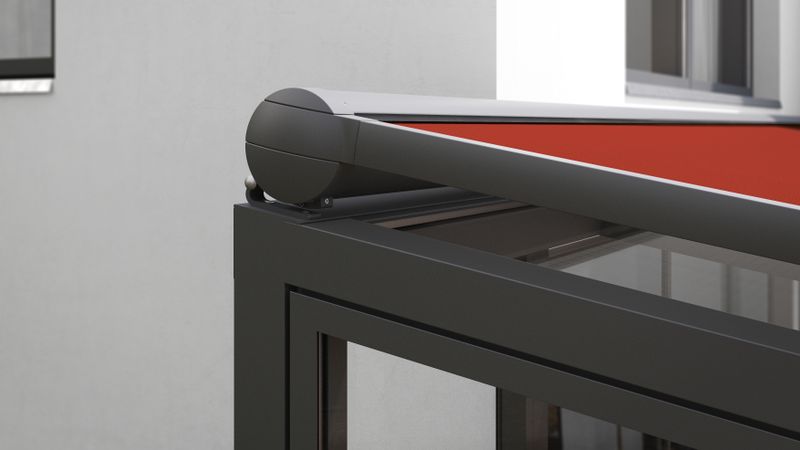 Detail view of the cassette of the markilux 8850 on-glass awning with red fabric cover on anthracite winter garden