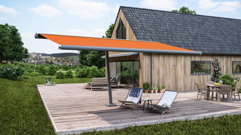 Awning parasol markilux planet with orange awning cover in front of a wooden house.