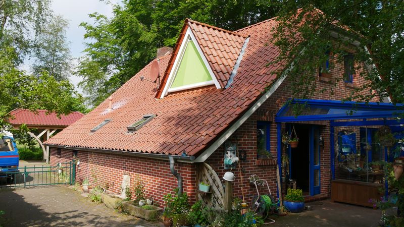 Casa de tijolo com mansarda triangular e toldo triangular verde markilux 893.