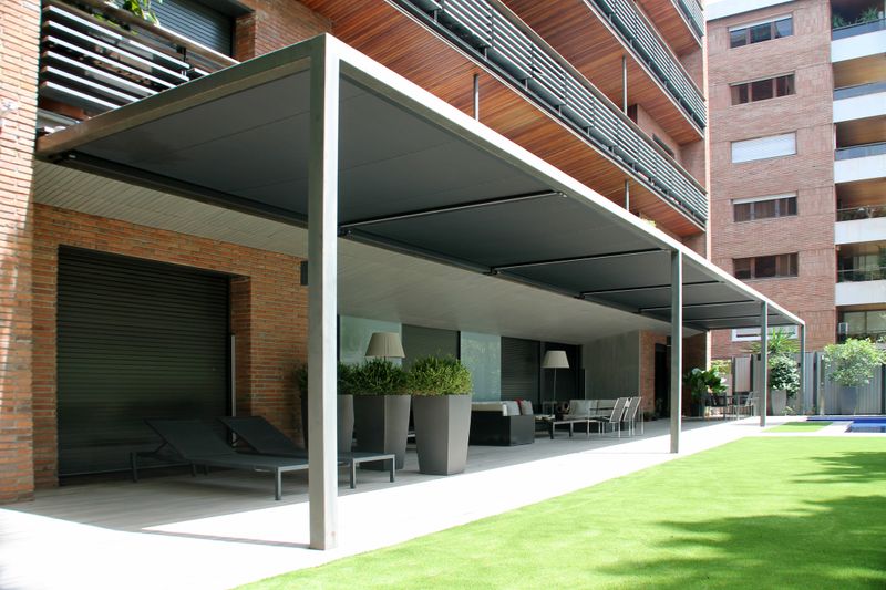 Cobertura do terraço de um hotel com o toldo de vidro markilux 770 top com cobertura em tecido preto.