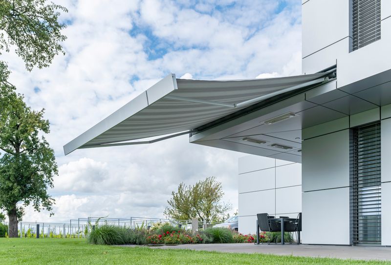Gray cassette awning markilux 3300 on a modern gray cube building.