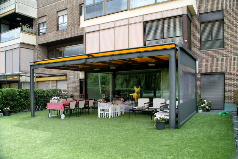Teto do terraço equipado com um toldo markilux 770 em vidro com tecido amarelo e estore vertical 776 com cobertura em tecido antracite e janela panorâmica.