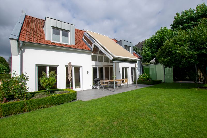 Casa unifamiliar blanca con claraboya que se extiende sobre la terraza, cubierta con toldo de cristal markilux 8800.