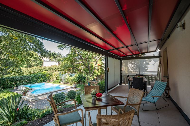 markilux pergola stretch with red fabric cover: reference object in a private garden. roofing of the terrace.