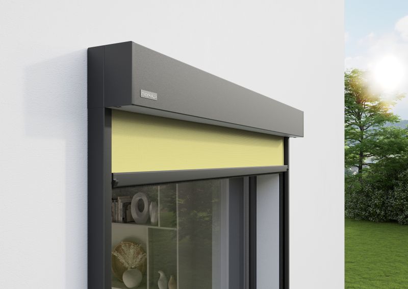 Detail view of vertical cassette awning markilux 625: gray frame, light yellow fabric cover, wall mounted.