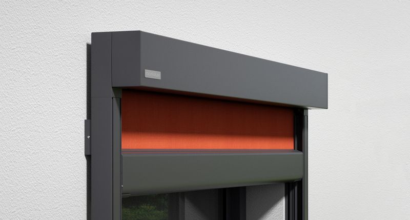 Detaljvy av vertikal kassettmarkis markilux 776: grå ram, orange tygduk, väggmonterad.
