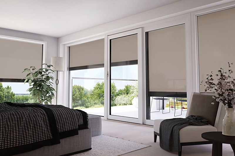 Vertikale Kassettenmarkise für Fenster mit beigem Tuch an einem Schlafzimmer mit großer Fensterfront