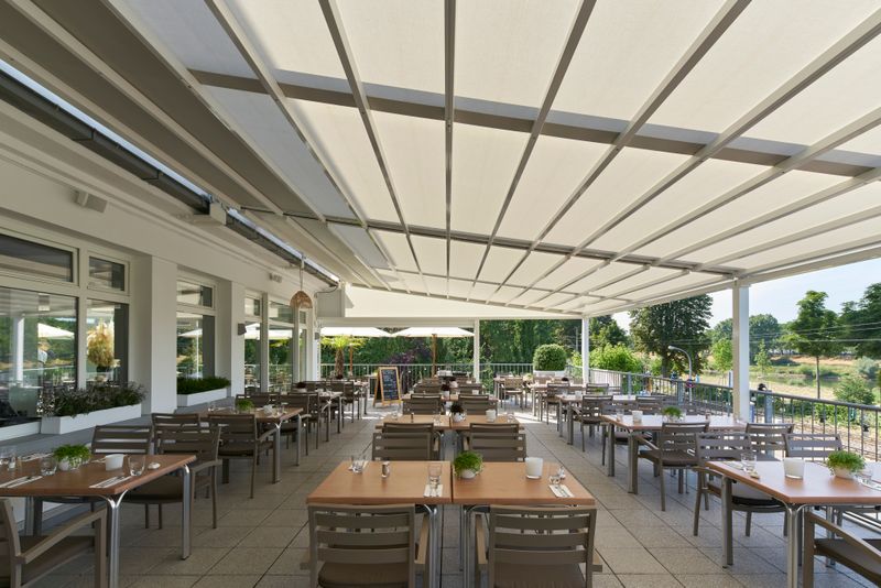 Reference picture of a pergola stretch with white frame and cream fabric cover on the roof terrace of the bootshaus in Mannheim, Germany