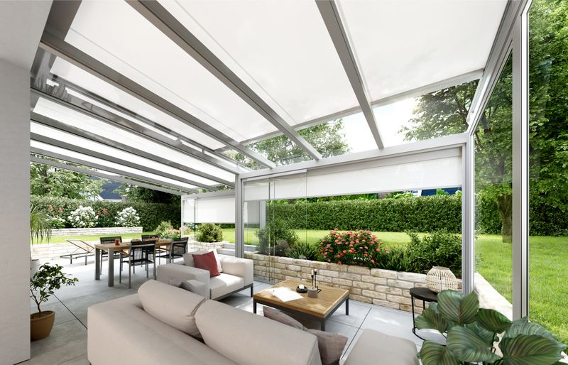 Toldo de cristal markilux 770 sobre el tejado de una veranda con marco blanco y lona de tejido crema. Al fondo se ve un gran jardín.