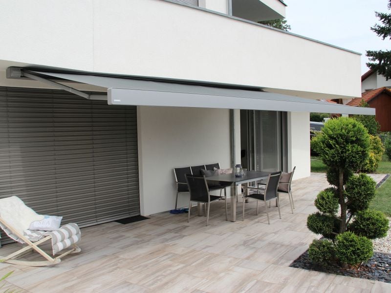 Toldos de cassete markilux 970 em cinza sobre parede de terraço rebocada de branco