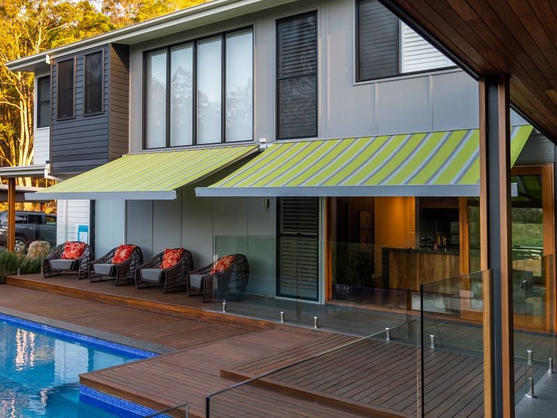 Cassette awning markilux 970 green-blue striped on hotel courtyard with pool