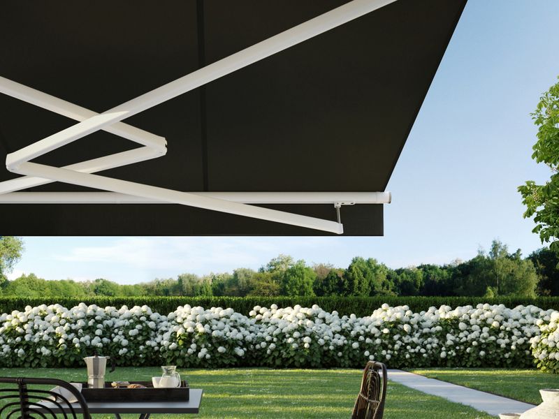 Folding arm awning markilux 1700 in white with dark fabric as stretch variant