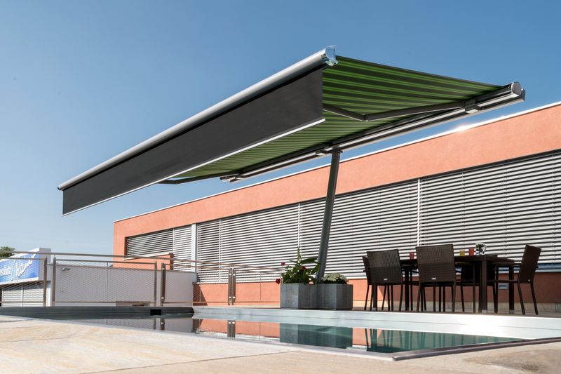 Awning parasol markilux planet with green striped fabric cover and black shadeplus by a pool.