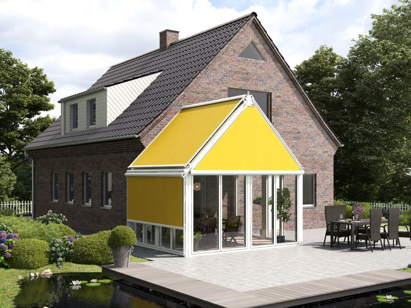 View from the garden on a brick house with attached winter garden, which is adjacent to a terrace with a pond. The winter garden has awnings for shading. The gable is equipped with a yellow triangular blind markilux 893.