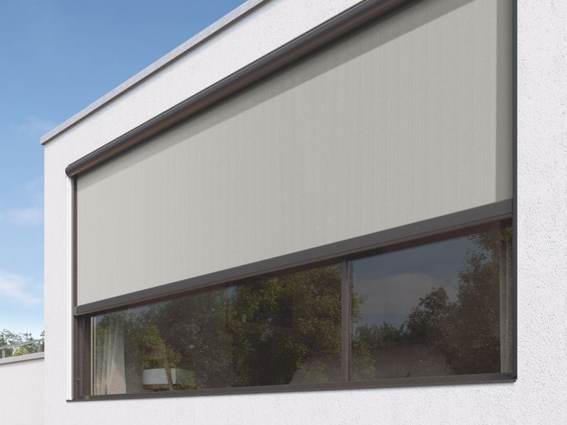 Vista detalhada do toldo vertical blaind awning markilux 876, cobertura de tecido cinza, sobre um edifício de gesso branco.