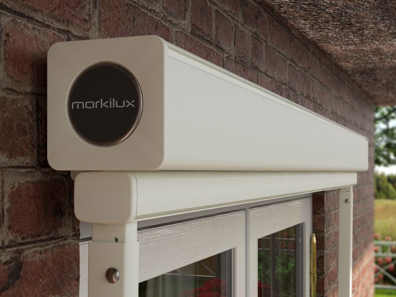 Detail view of drop-arm cassette awning markilux 730: white frame, retracted fabric cover, wall mounted.
