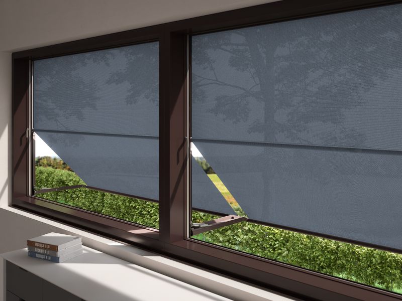 Vista do interior para o exterior: janela com marquisolette markilux 740 com cobertura em tecido cinzento, estendida.