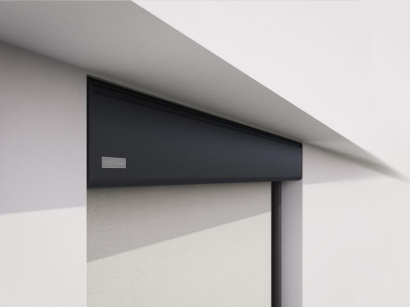 Detailansicht einer grauen markilux Vertikalmarkise in einer Nische einer weißen Hauswand montiert.