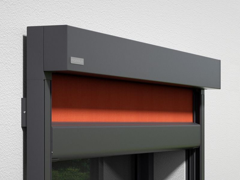 Vista detalhada do toldo de lona vertical Markilux 776: moldura cinzenta, cobertura de tecido laranja, montado na parede.
