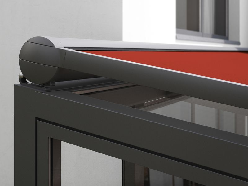 Detail view of the cassette of the markilux 8850 on-glass awning with red fabric cover on anthracite winter garden