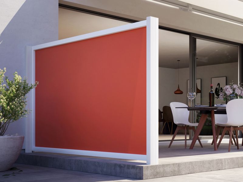 Casa com terraço e tela lateral vermelha formato markilux como sol e privacidade.
