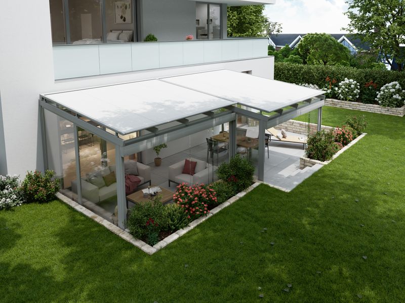 On-glass awning markilux 770 with white fabric cover and dark gray frame. The winter garden is located in front of a modern house and surrounding is a large garden.