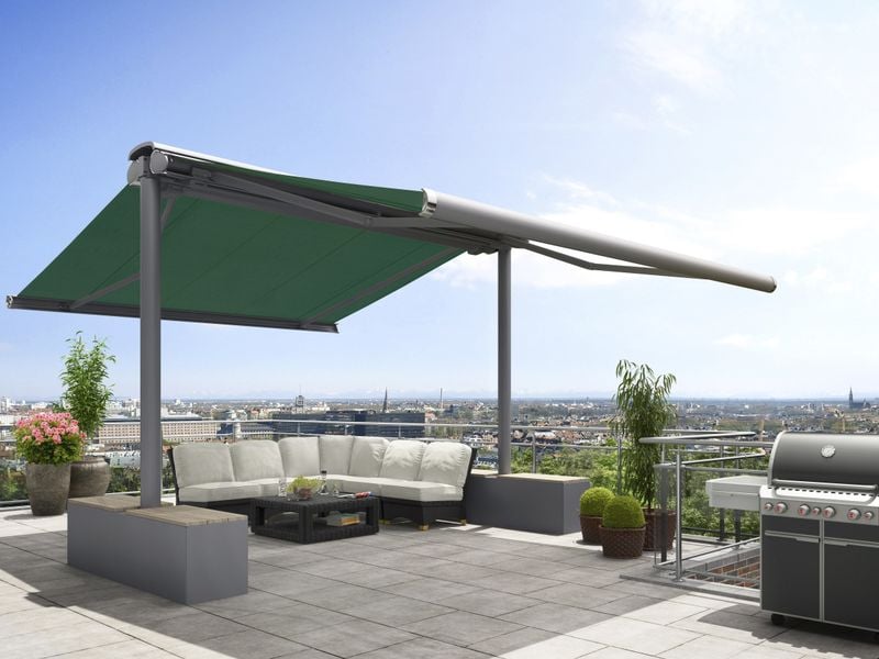 Awning stand system markilux syncra with green awning cover and gray frame, fixed with stabilisation boxes on a roof terrace overlooking the city.