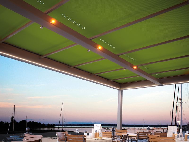 Terrasseoverdækning markilux markant med grøn markisedug og belysningsmuligheder, placering ved en havn.