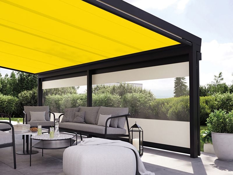 Gelbe Wintergartenmarkise an einem Terrassendach und frontal ist eine Vertikalmarkise mit Panoramafenster angebracht.