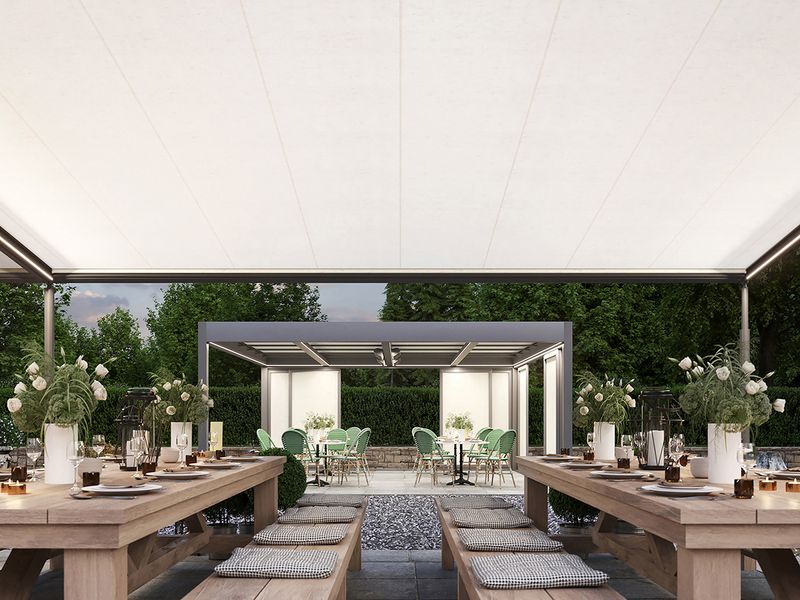 View of a restaurant terrace under a white markilux pergola classic. View of a seating area off the main terrace, covered by the markilux markant awning system.