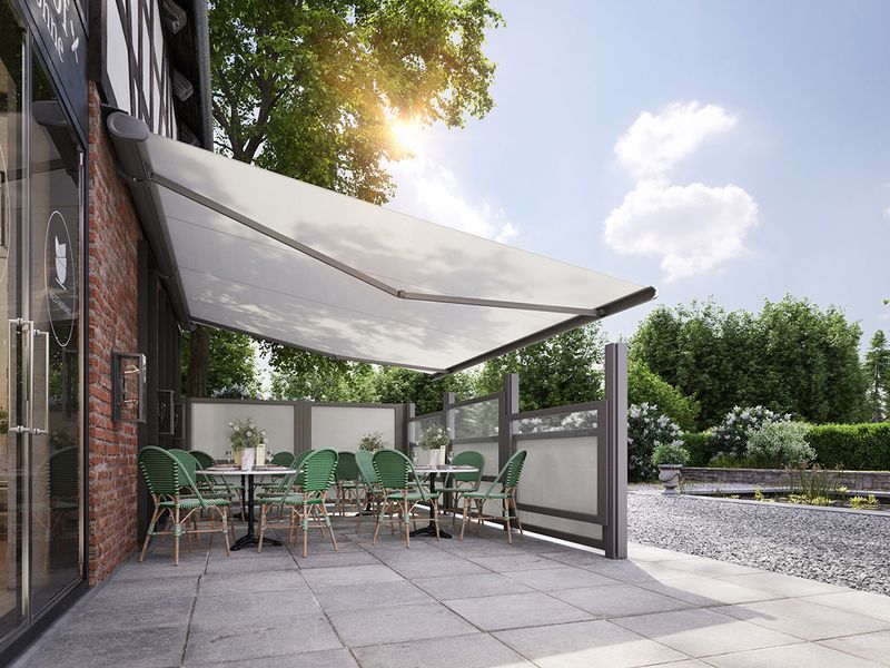 Terrace of an inn, covered with a white awning. As additional protection against wind serve the side elements markilux format in the same design as the awning.