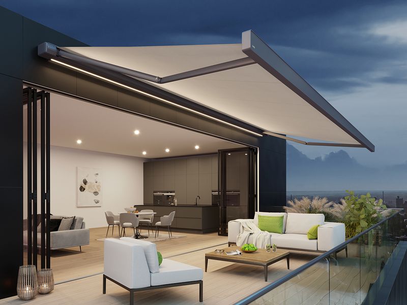 El markilux 970 con LED-Line en el casete y un tejido luminoso en una terraza por la noche.