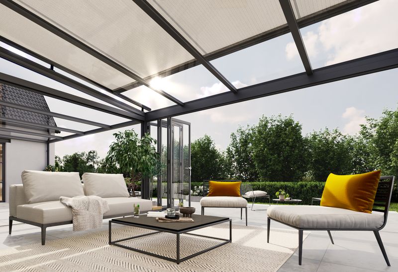 The markilux 7800 top glass awning with light awning cover on a modern conservatory makes the terrace look like an outdoor living room with a lounge area.