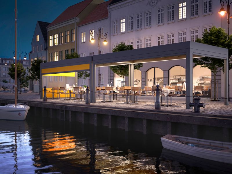 markilux markant en la orilla de un puerto como voladizo para la terraza de un restaurante. Escena nocturna con iluminación del toldo.