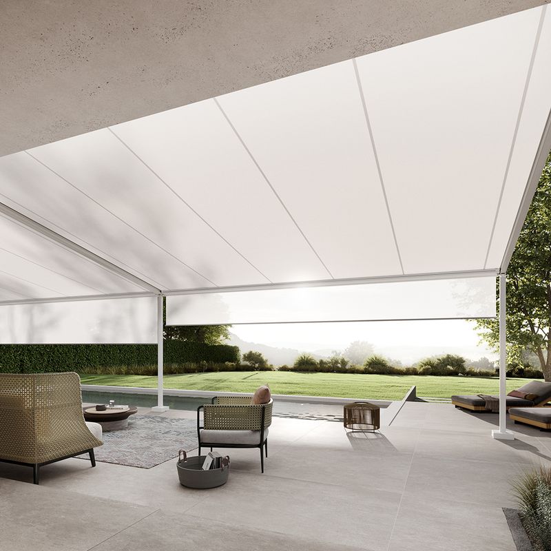 View below a white markilux pergola style with a view of the spacious garden with pool adjacent to the terrace. Shadeplus is integrated into the front profile of the pergola to protect against low sun.