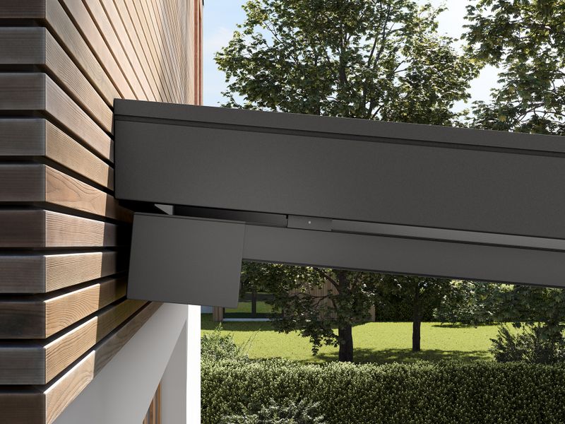 Detailed view of the profile of the cubic cassette of the markilux 679 under-glass awning, color anthracite metallic. The under-glass awning is installed under a patio roof that adjoins a modern detached house with a wooden façade.