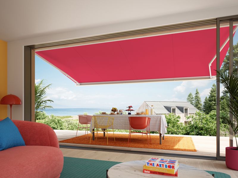 Udsigt fra et hus i skandinavisk stil til en terrasse dækket af en markise, MX-3'eren med et lyserødt markisedæksel.