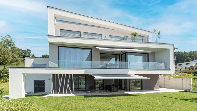 Casa a più piani con tenda da sole a cassonetto markilux 970 sopra la terrazza e il balcone.