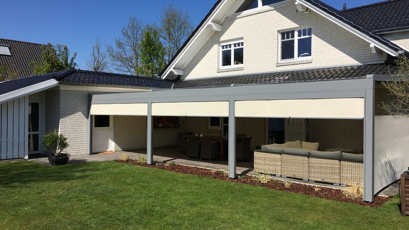 markilux pergola stretch med beige duk i kombination med vertikalmarkiser på ett småhus.