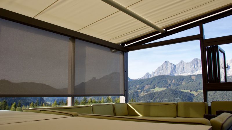 As janelas de uma estufa são parcialmente sombreadas com o toldo vertical markilux 625.